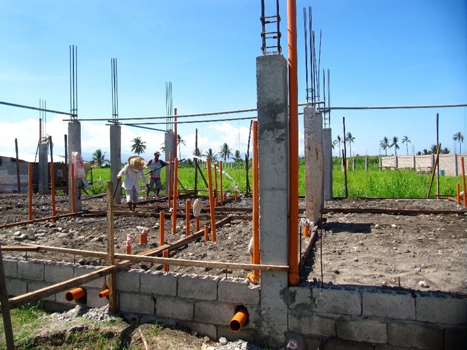 Photo showing columns, wirings, and plumbing at ongoing construction